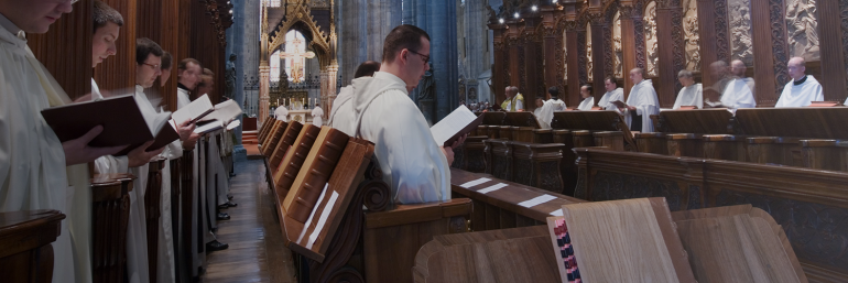 Religious wearing vestments praying in choir in a church